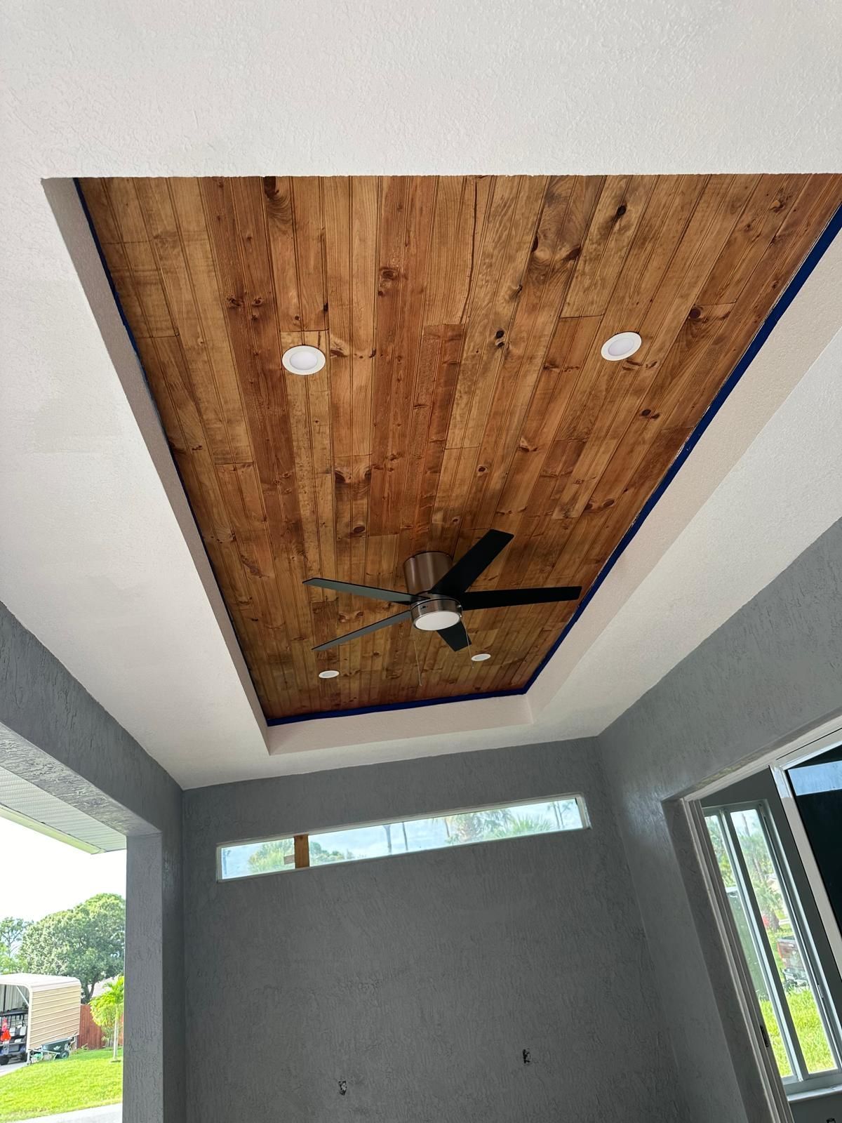A room with a wooden ceiling and a ceiling fan.