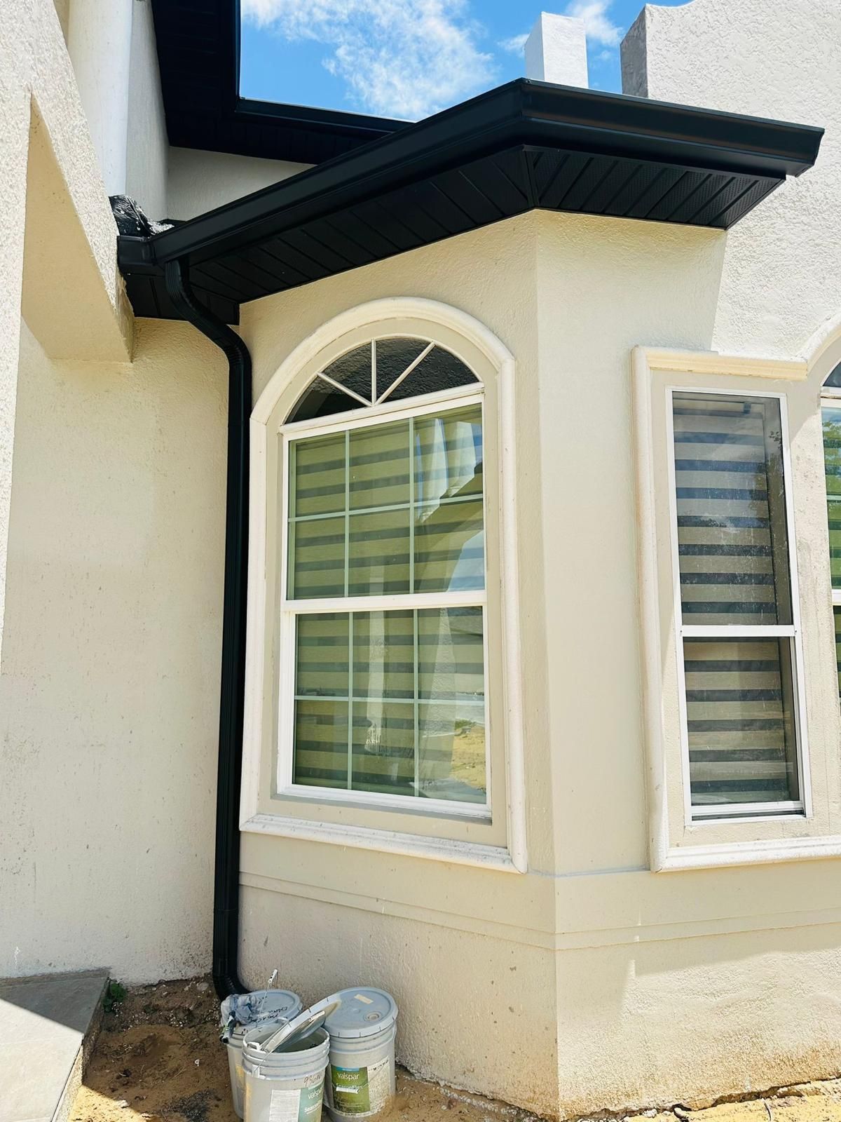 A white house with a bay window and a black gutter.