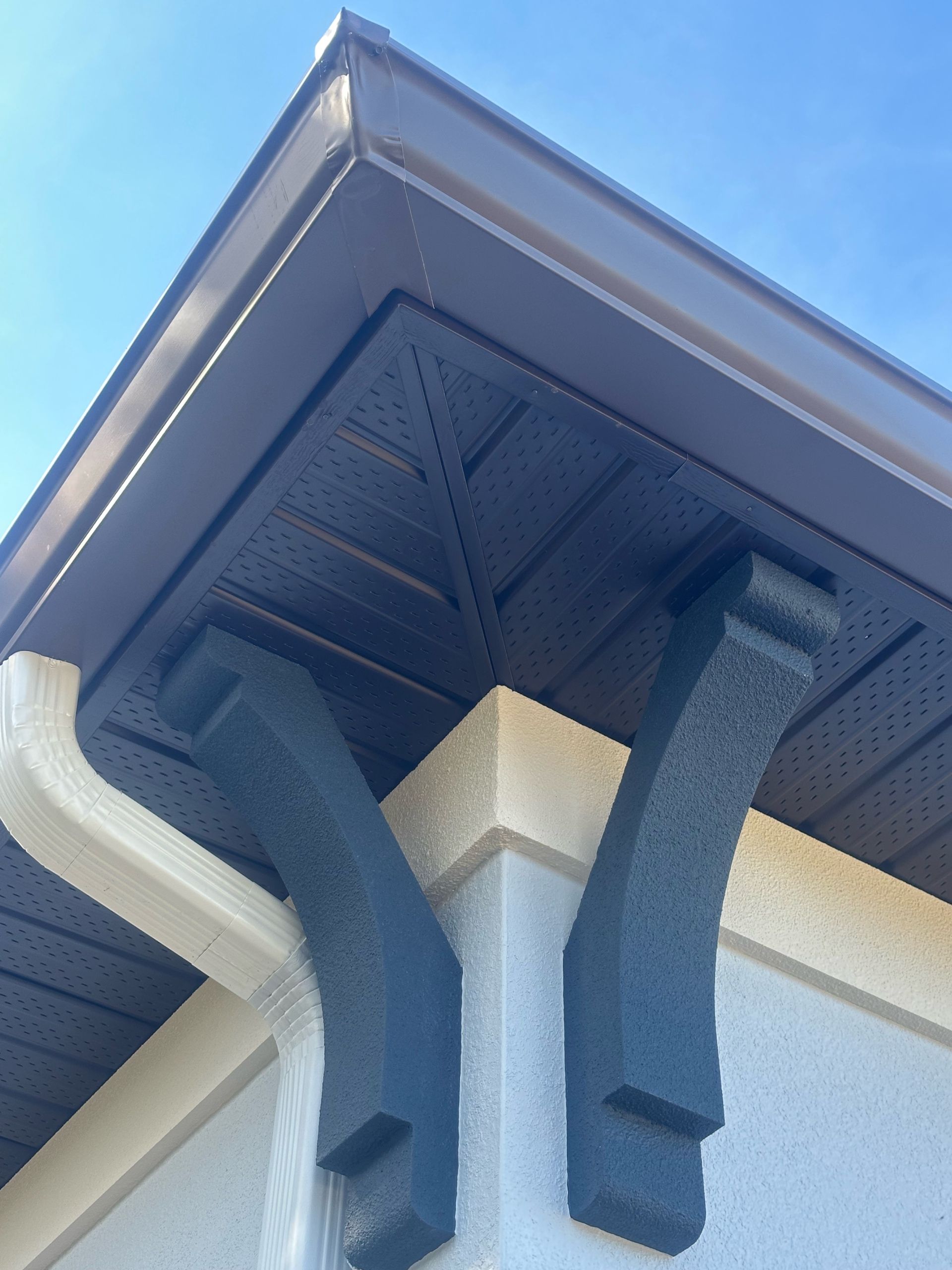 A close up of a gutter on a house with a blue sky in the background