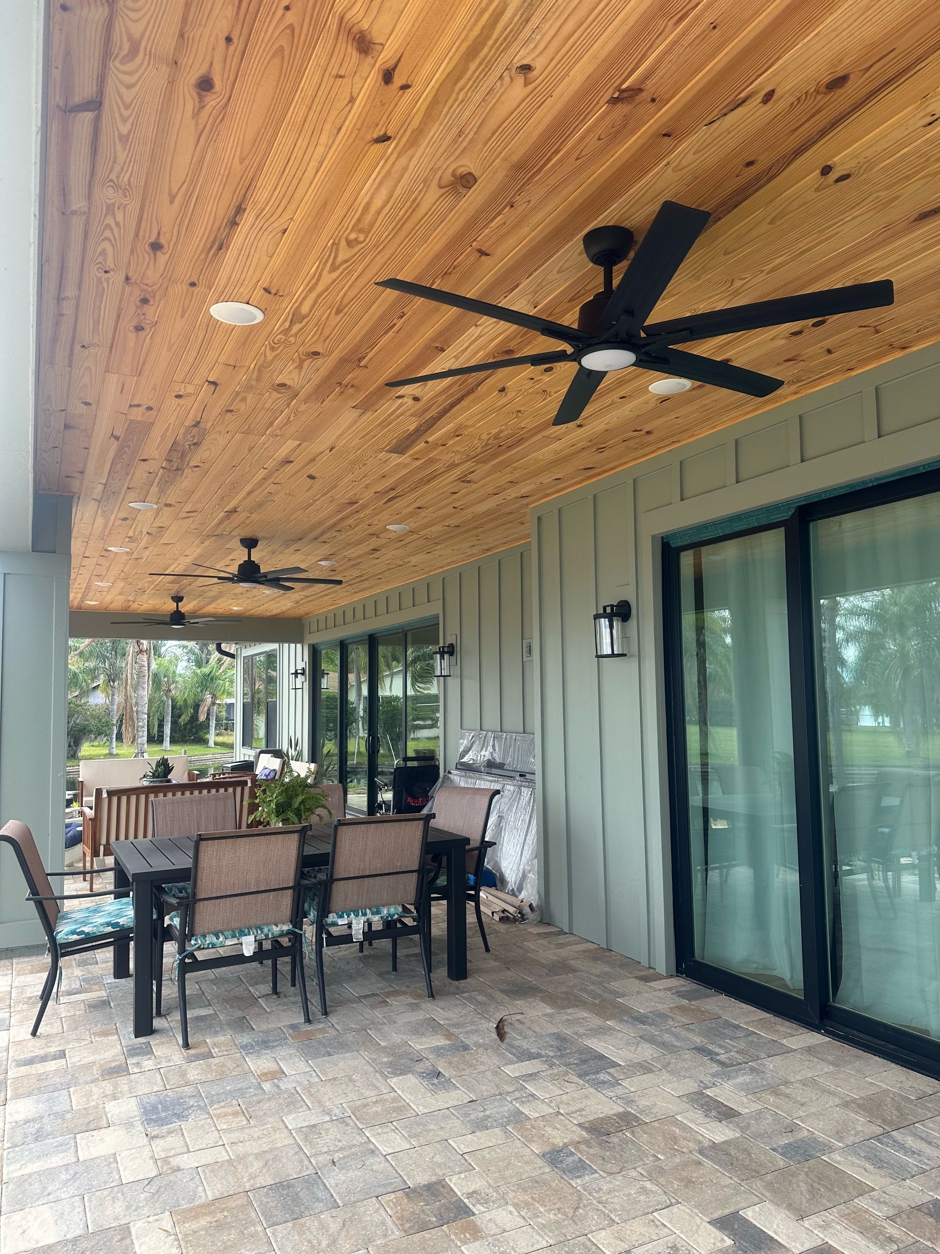 A patio with a wooden ceiling and a ceiling fan