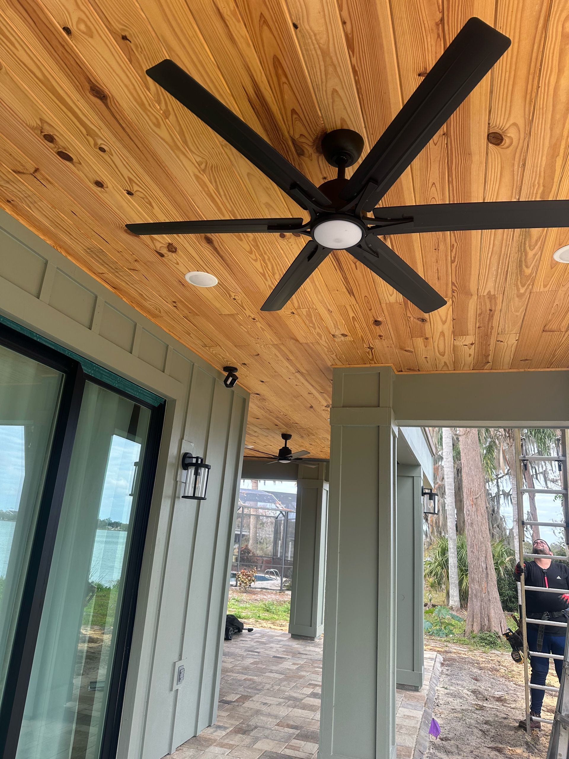 A ceiling fan is hanging from the ceiling of a porch.