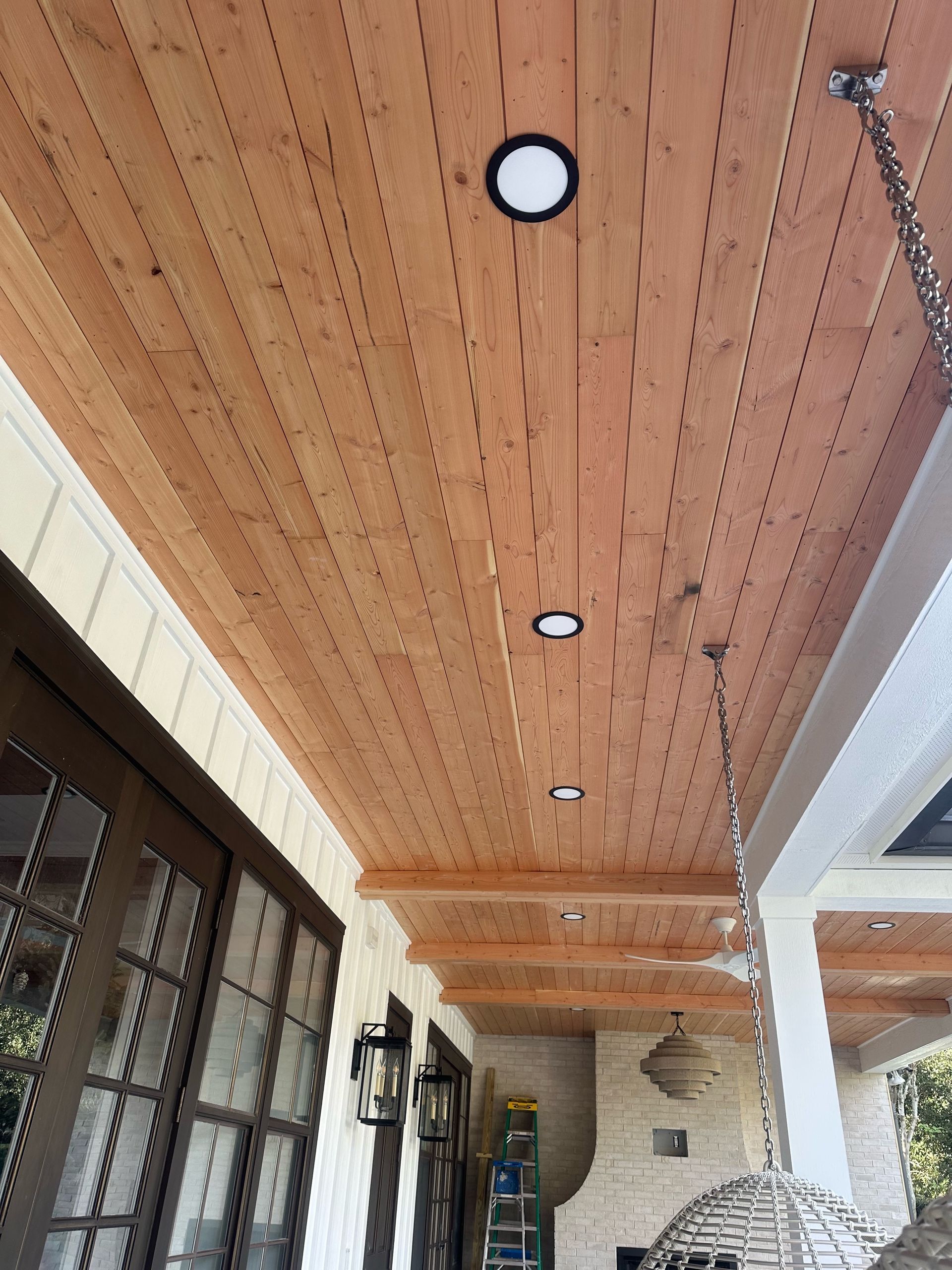 A porch with a wooden ceiling and lights on it