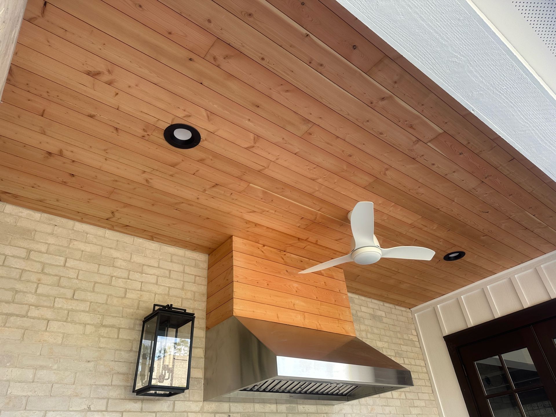A wooden ceiling with a stainless steel hood and a ceiling fan
