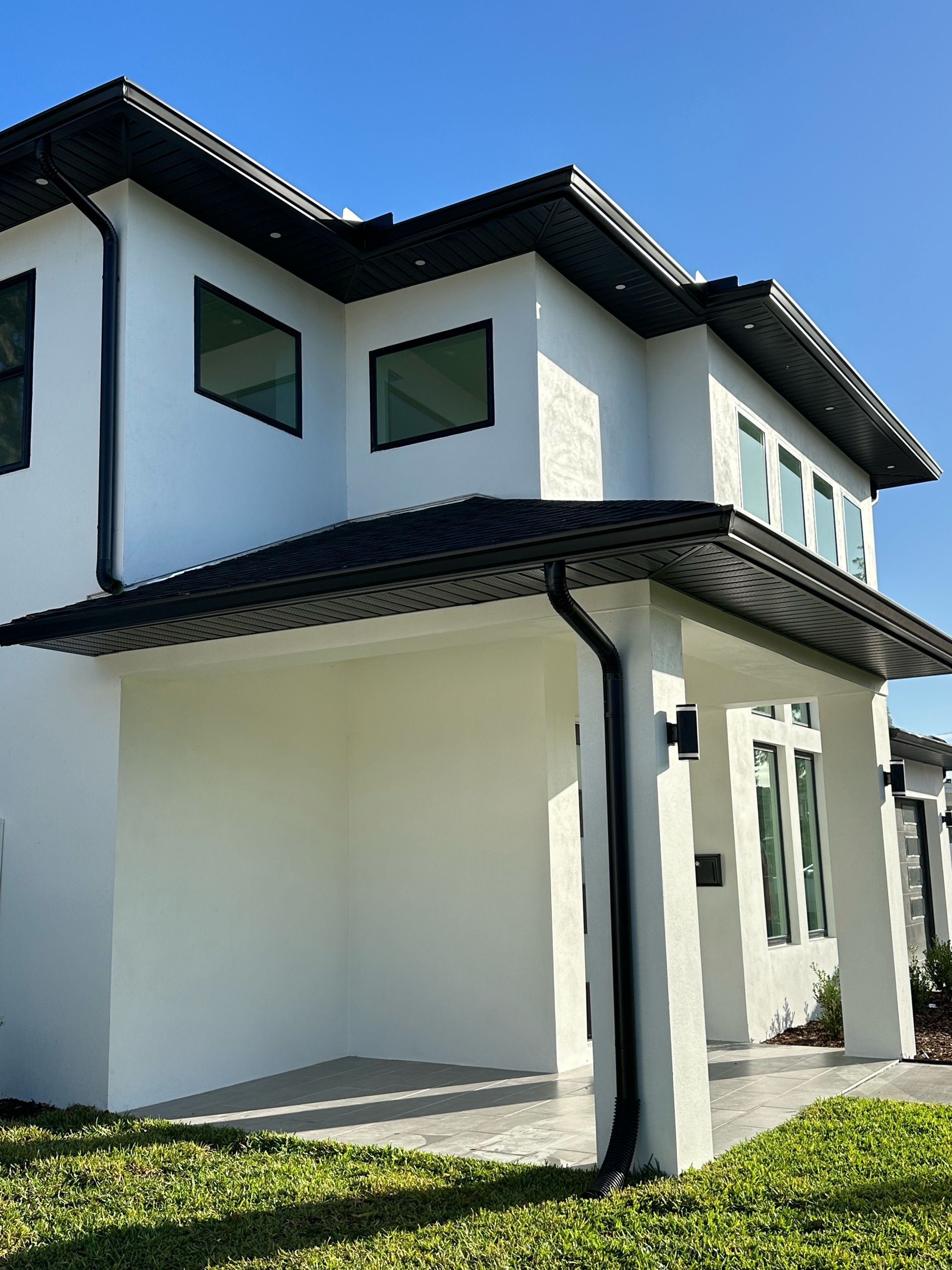 A white house with black windows and a black roof