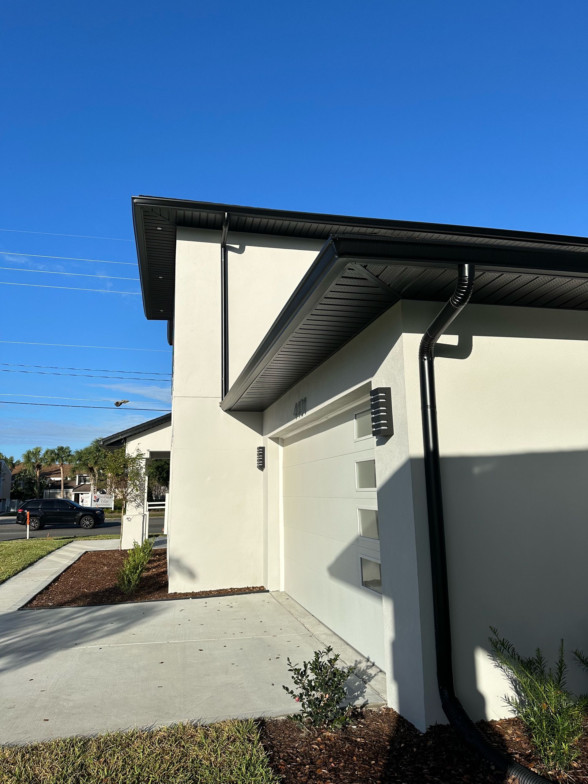 A white house with a black gutter on the side of it.