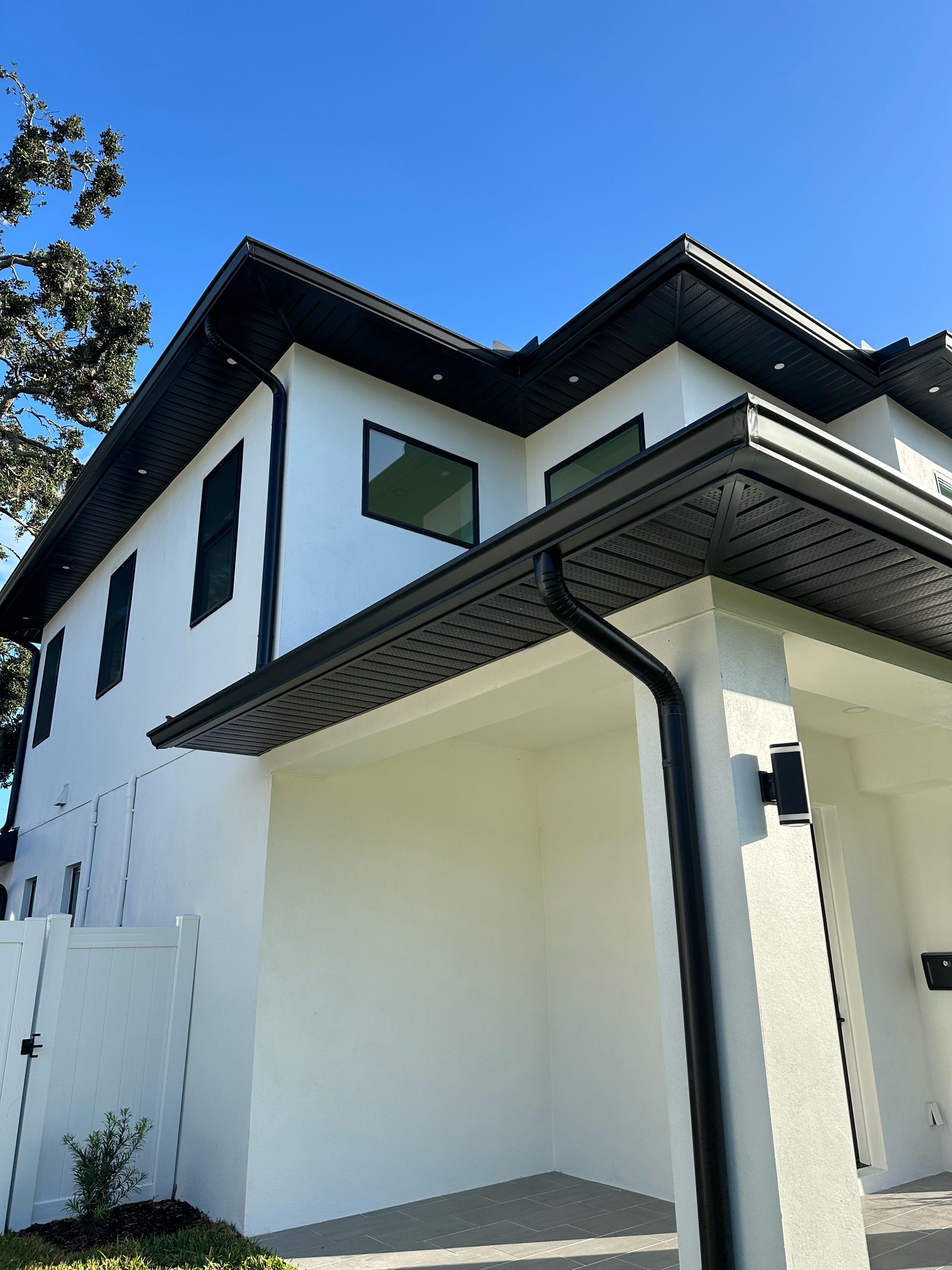 A white house with a black gutter and a blue sky in the background.
