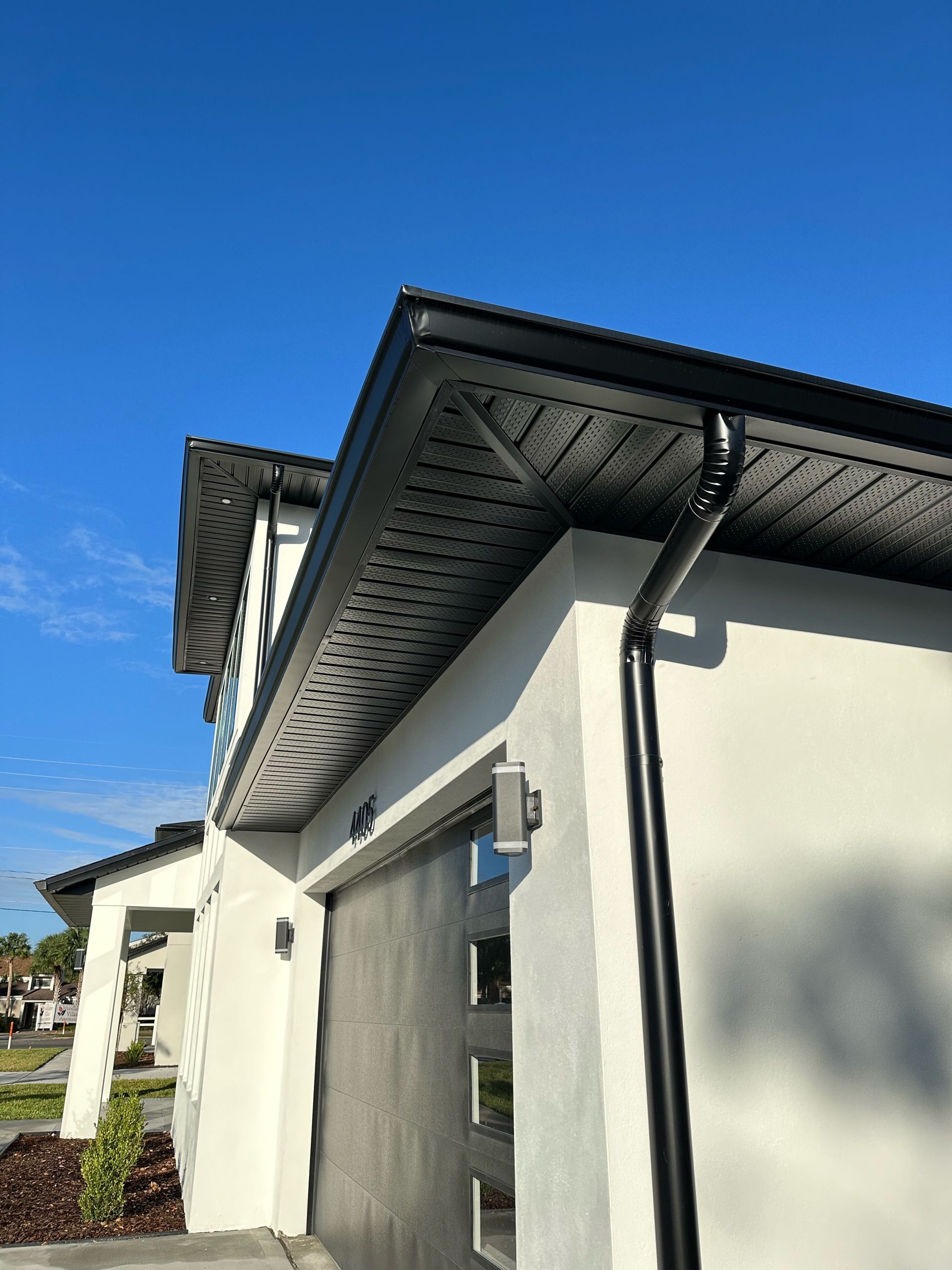 A white house with a black gutter on the side of it.