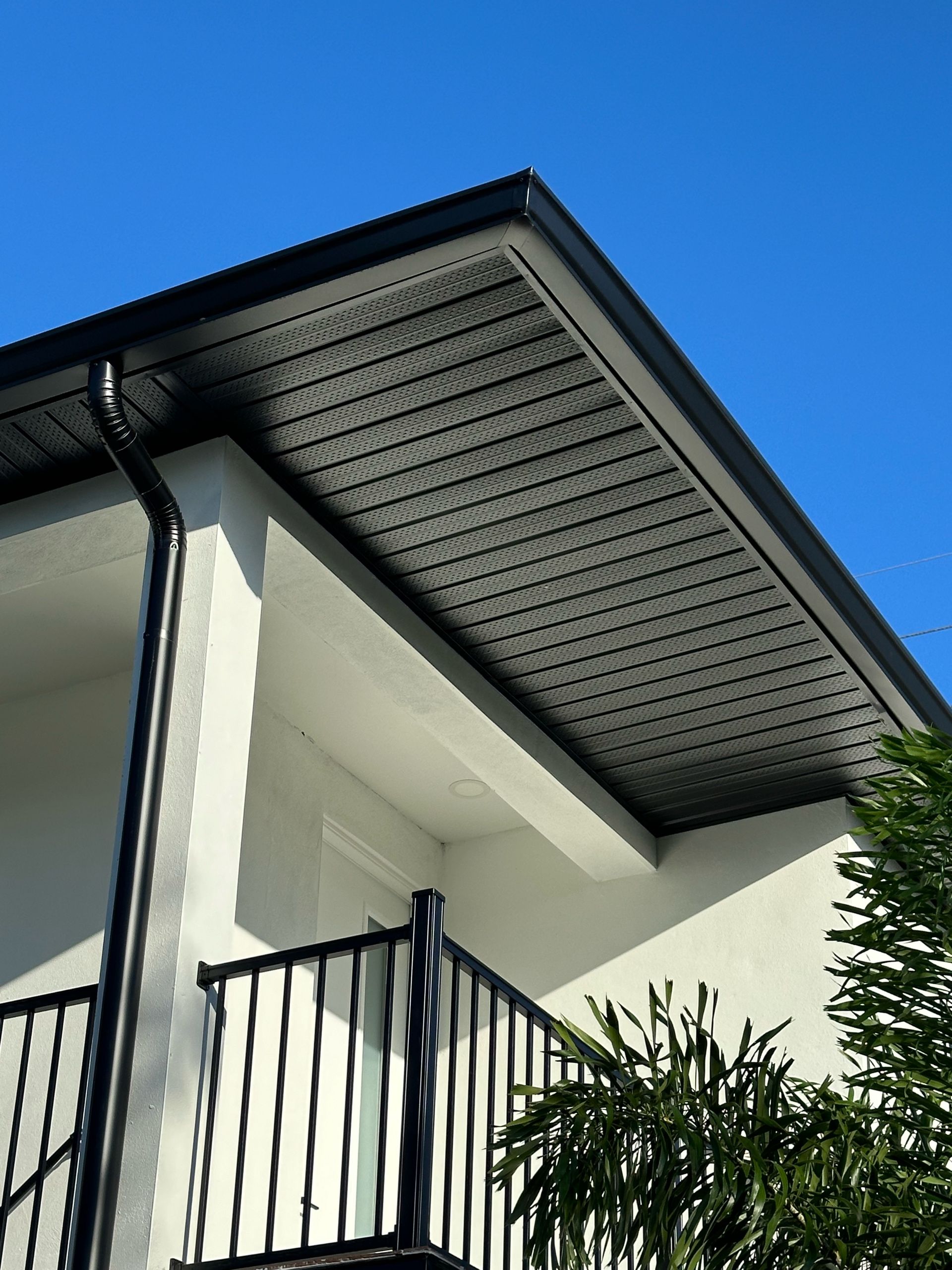 A white house with a balcony and a black gutter.