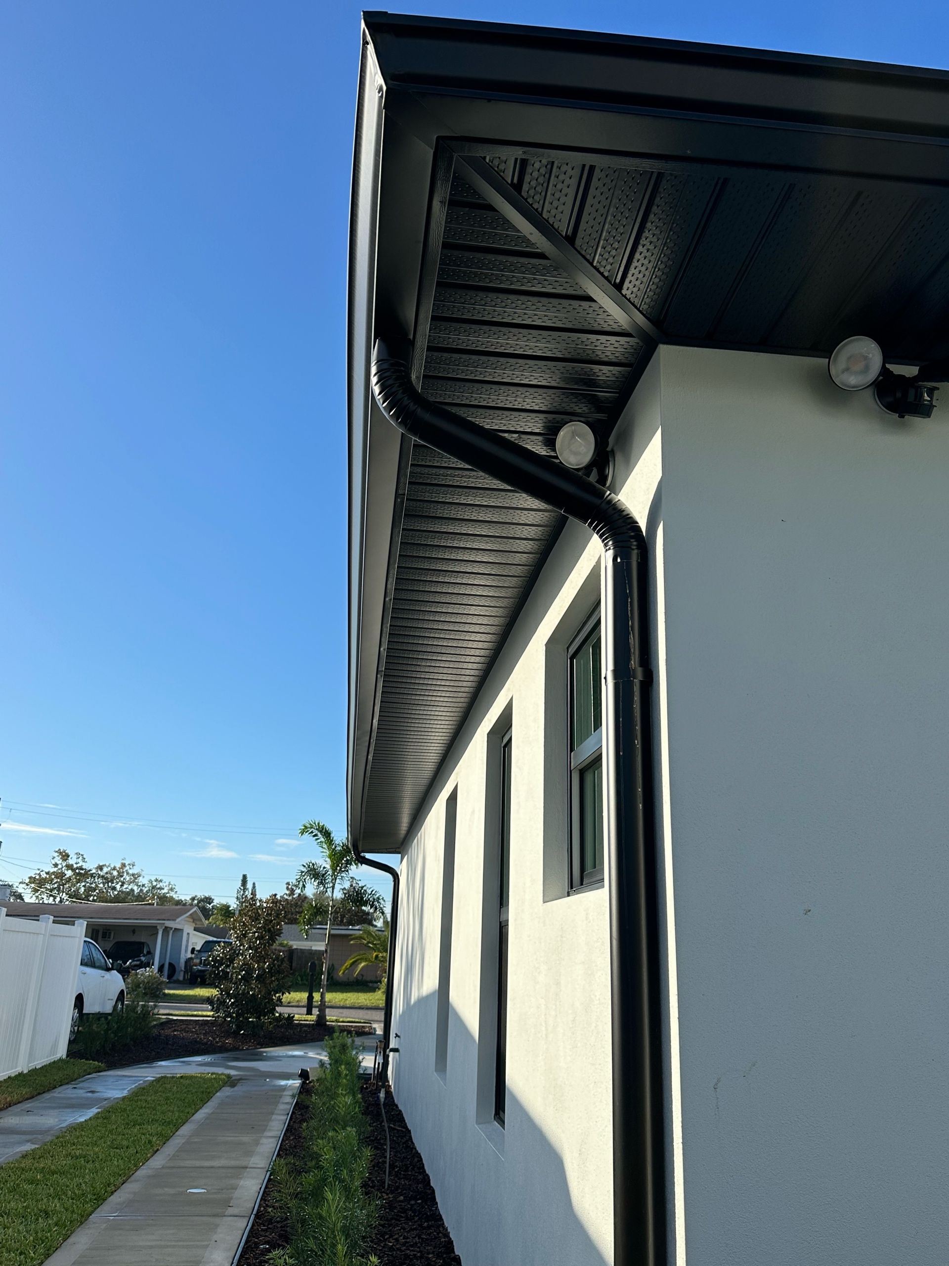 A white house with a black gutter on the side of it