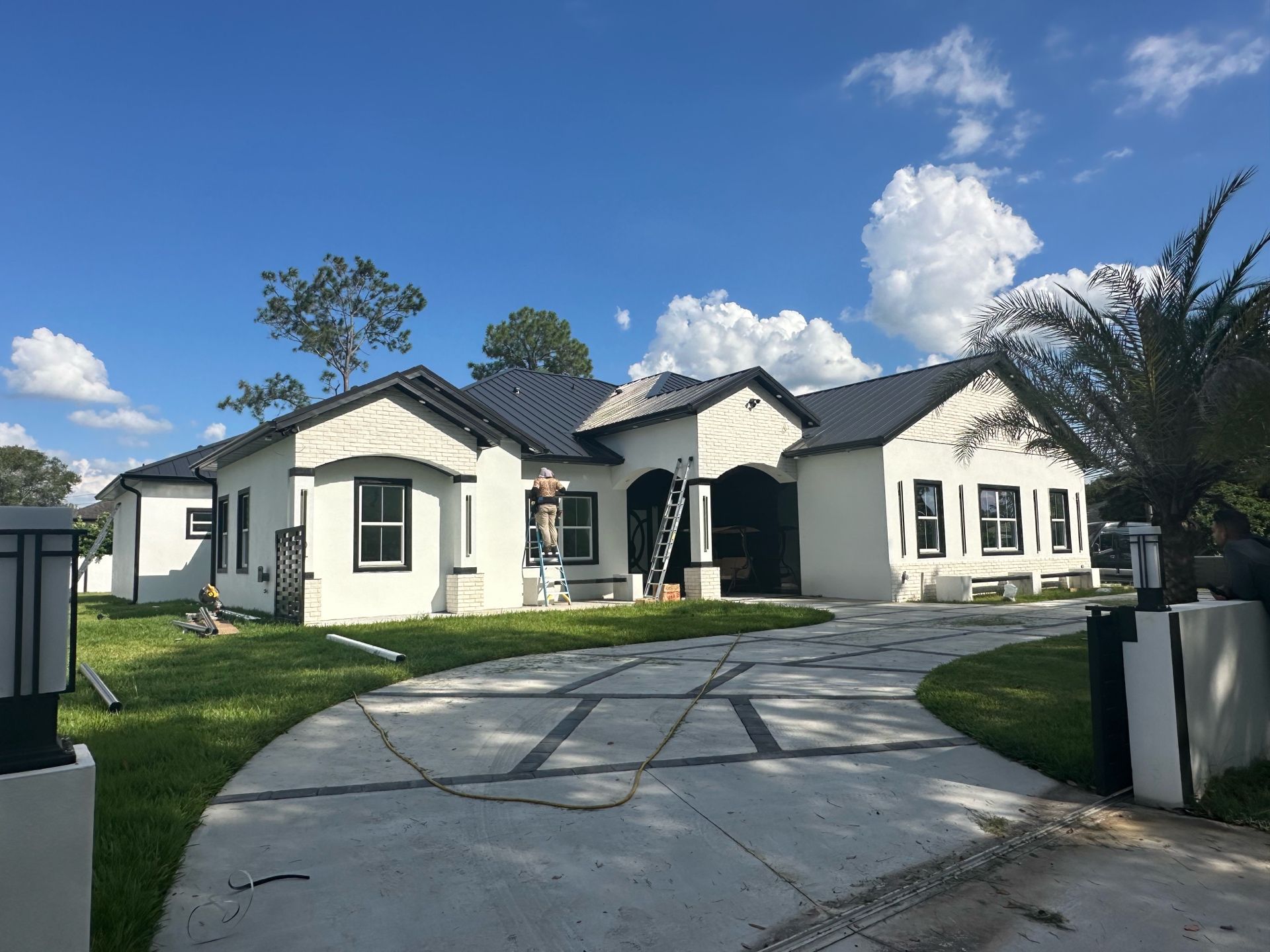 A large white house with a black roof is being painted.