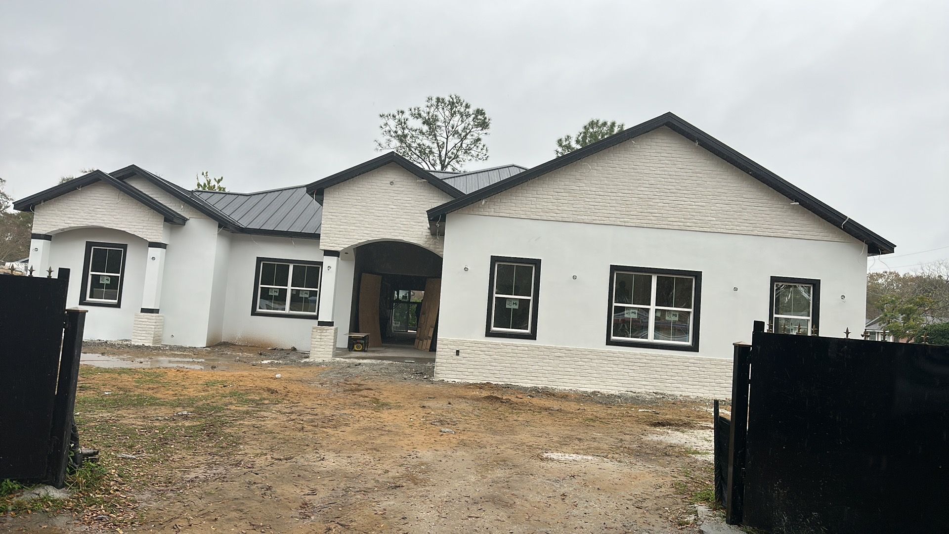 A large white house with a black roof is being built.