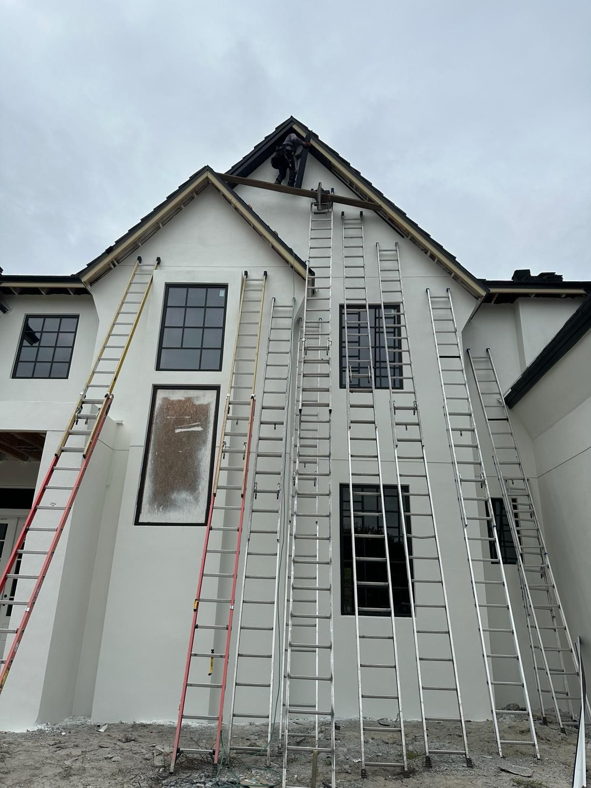 A row of ladders are lined up in front of a white house