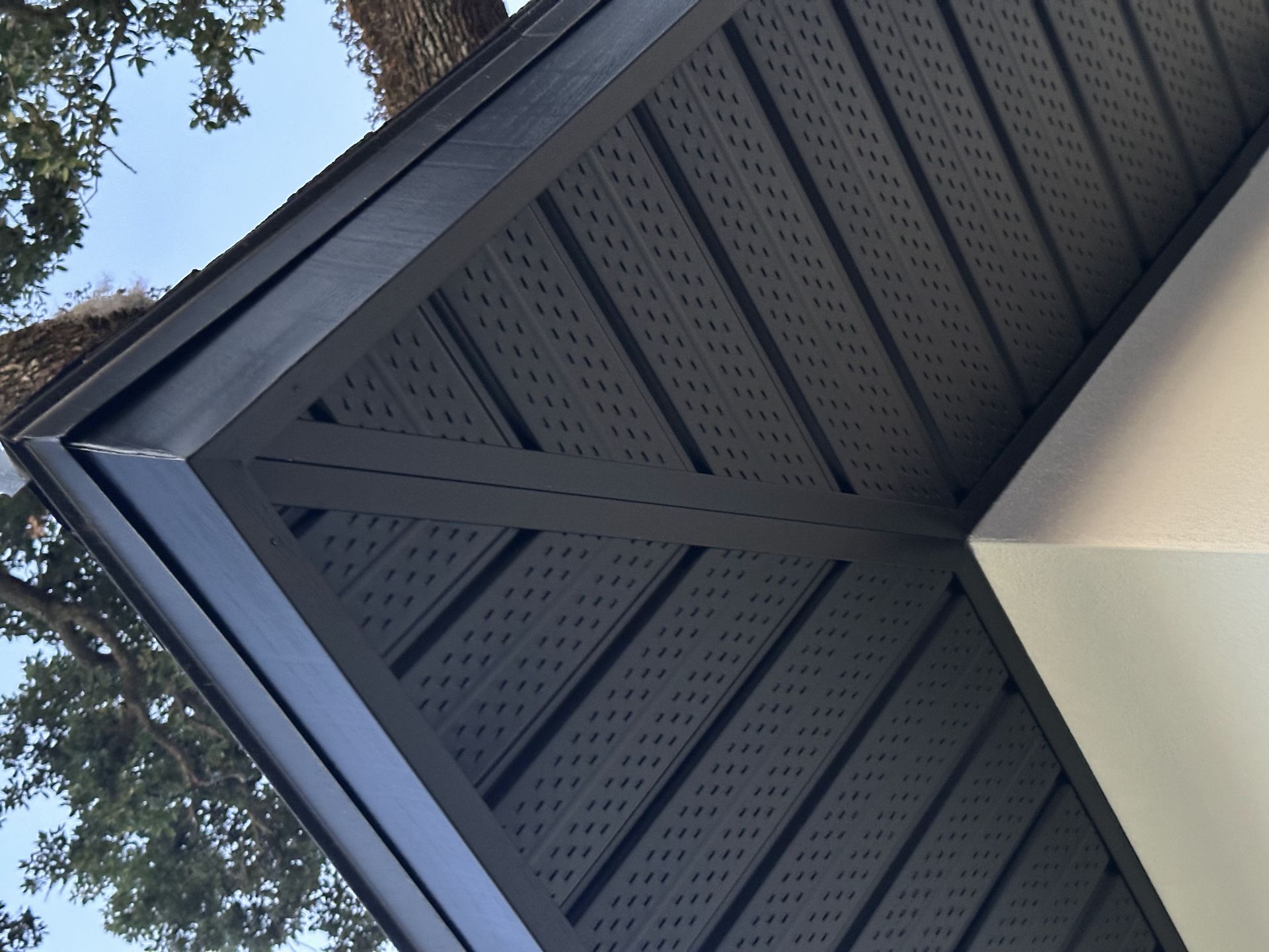 A black roof with a tree in the background