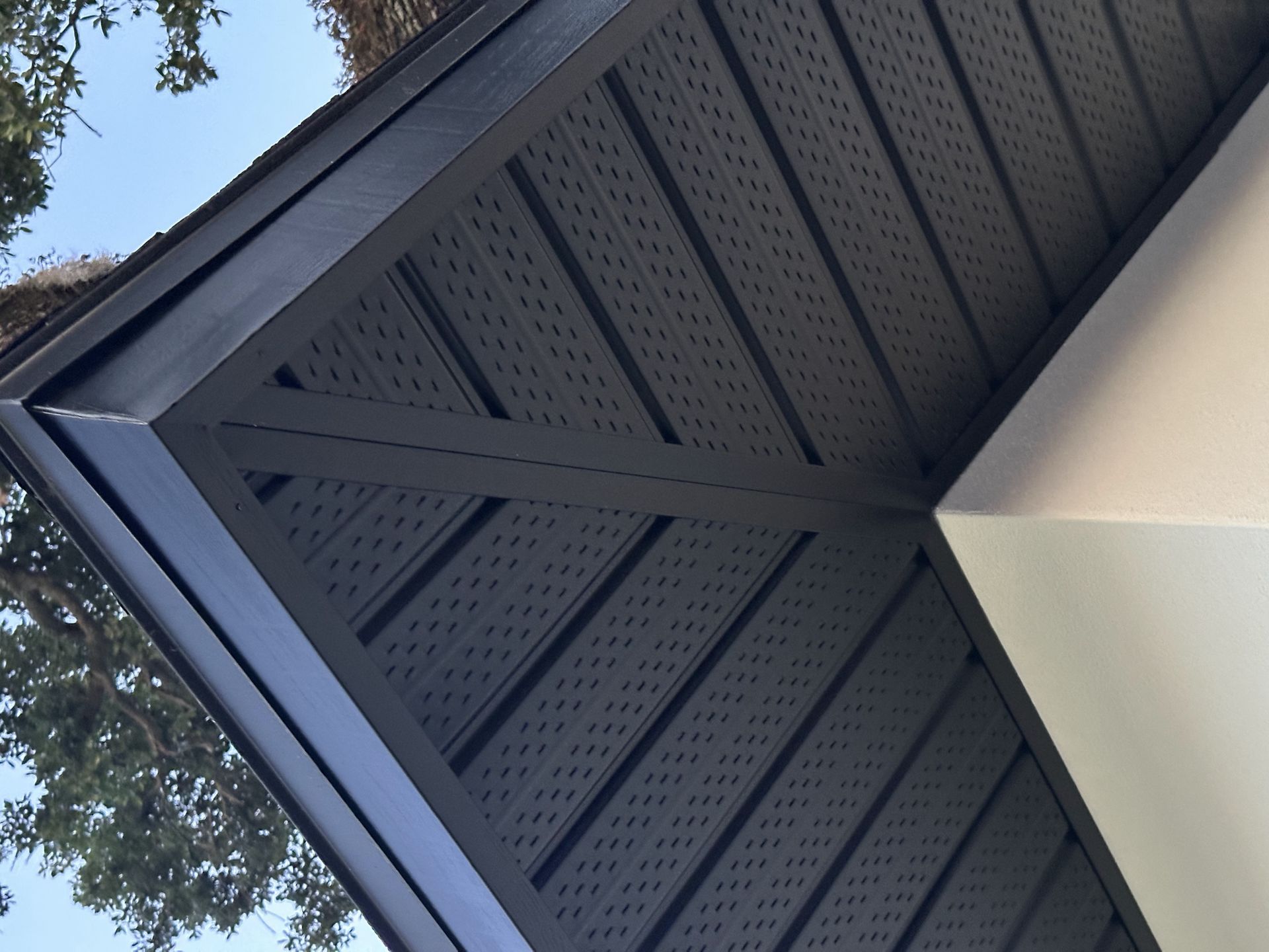A black roof with a tree in the background