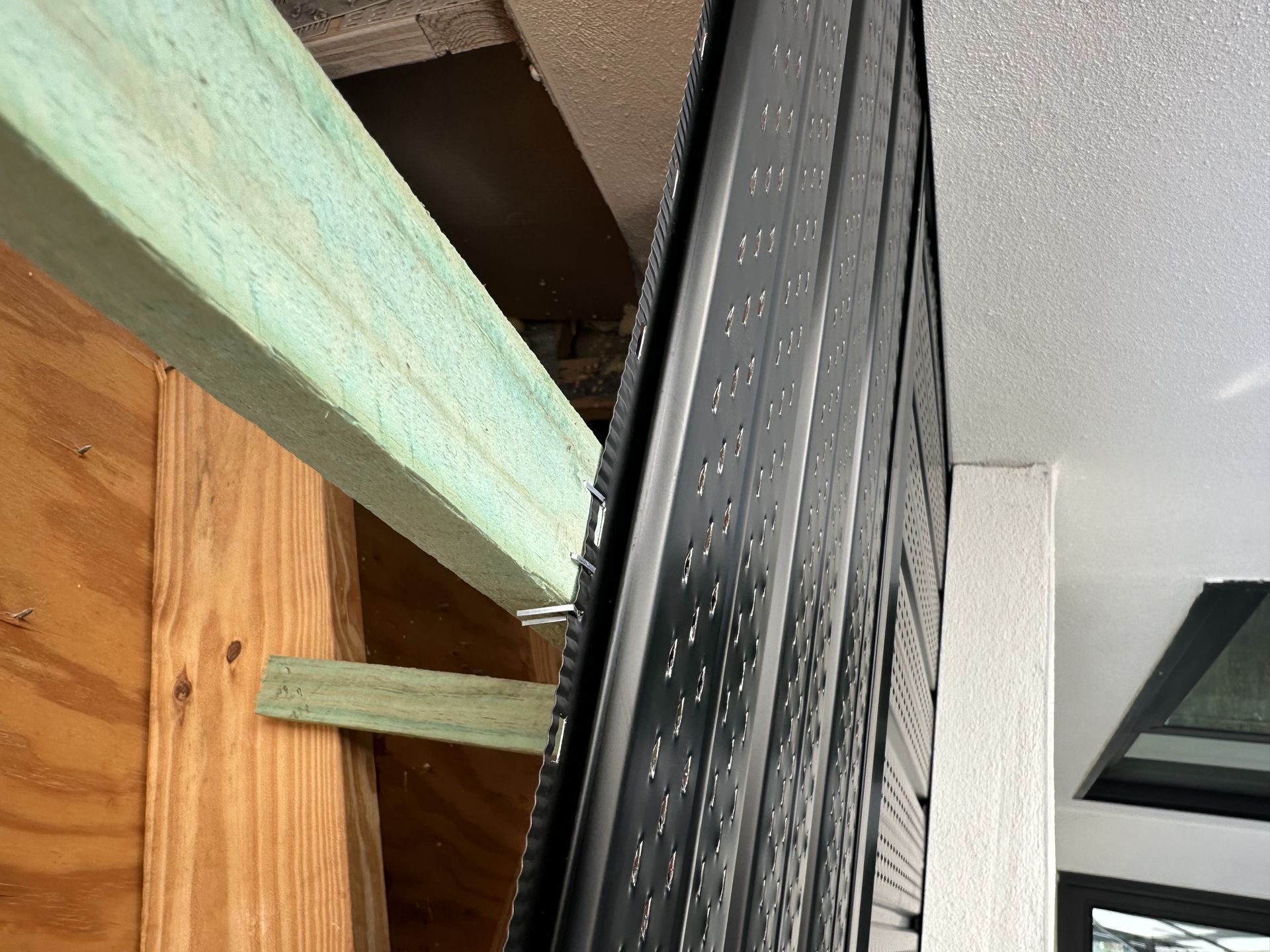 A close up of a wooden beam and a metal beam on a wall.