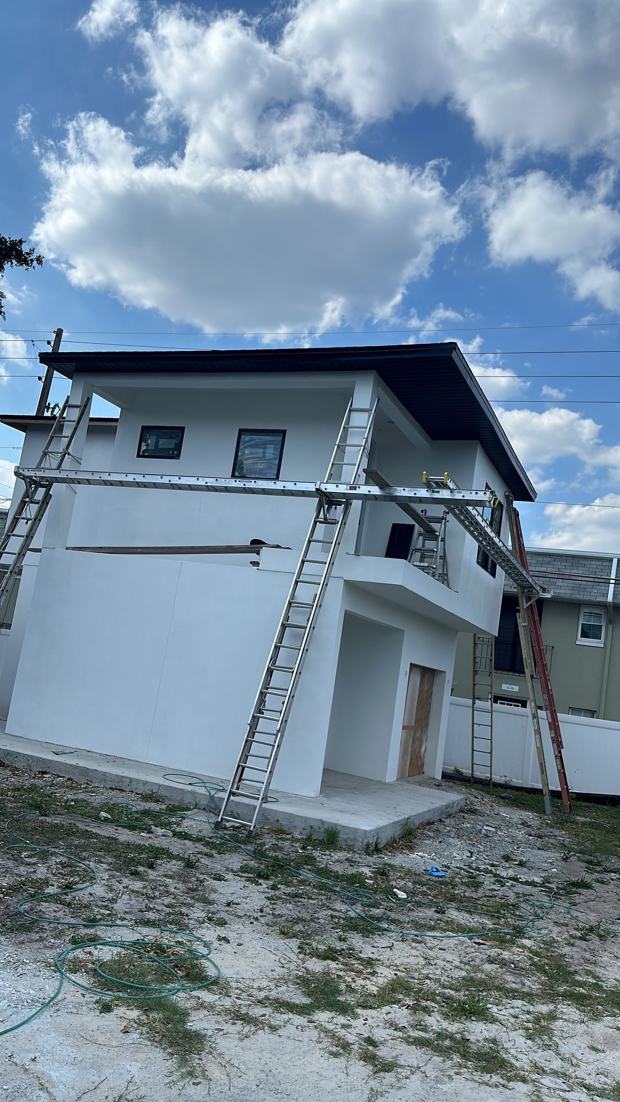 A white house with a black roof is being painted.