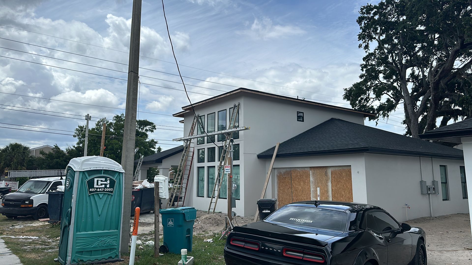 A black car is parked in front of a house under construction.