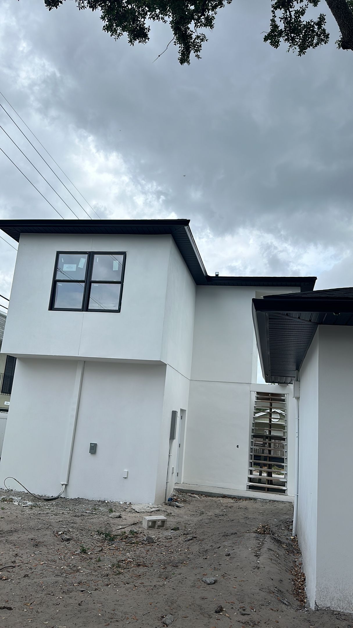 A white house with a black roof is under construction.