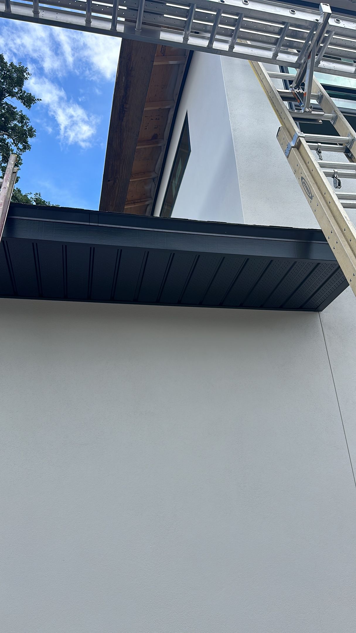 A white house with a black gutter on the side of it.