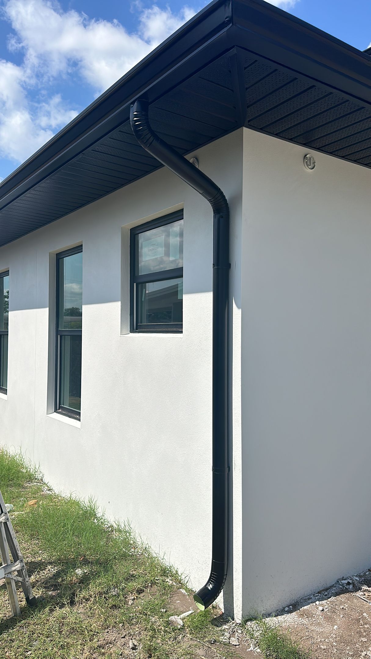 A white house with a black gutter and windows.