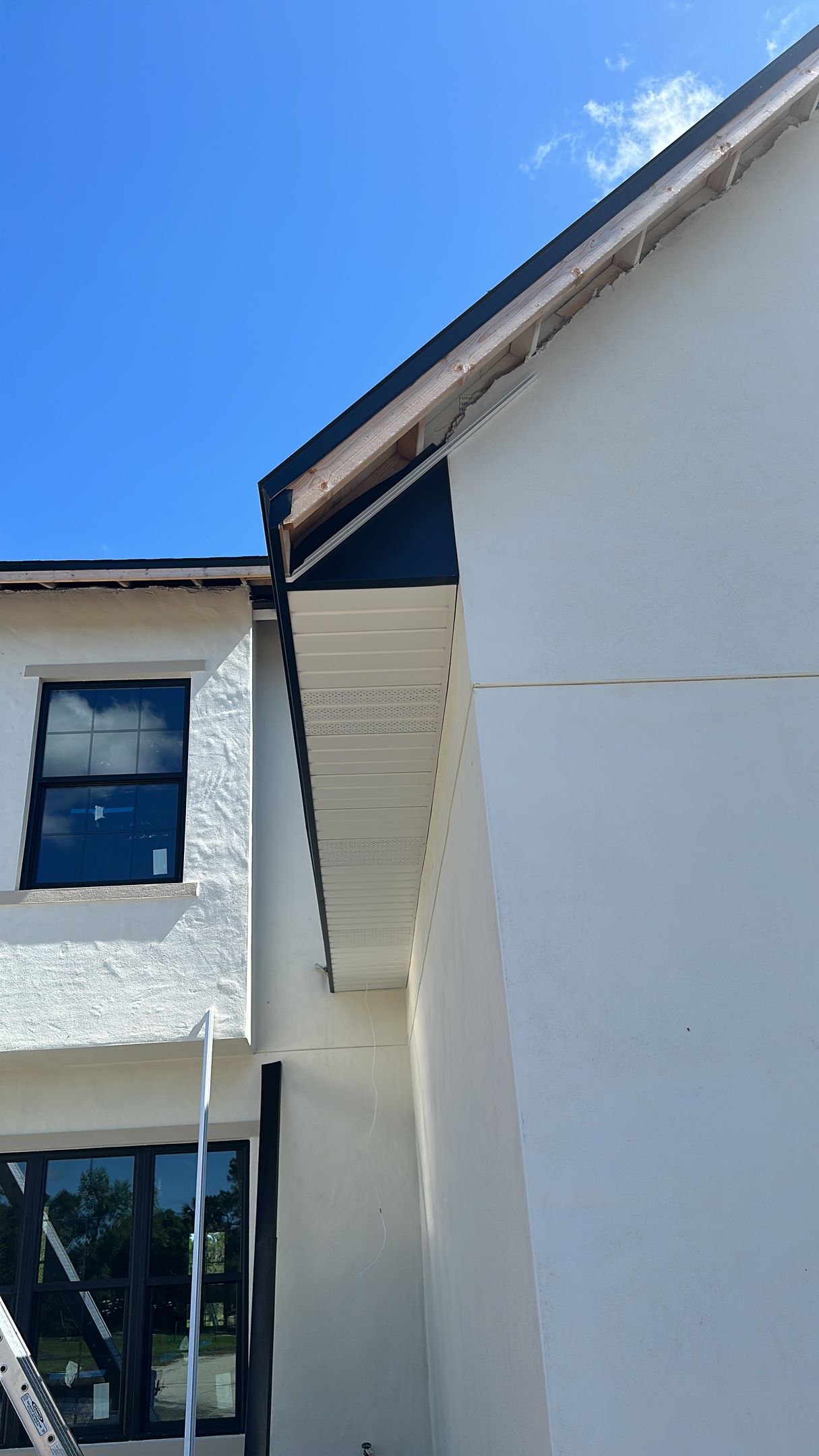 A white house with a black roof and a blue sky in the background.