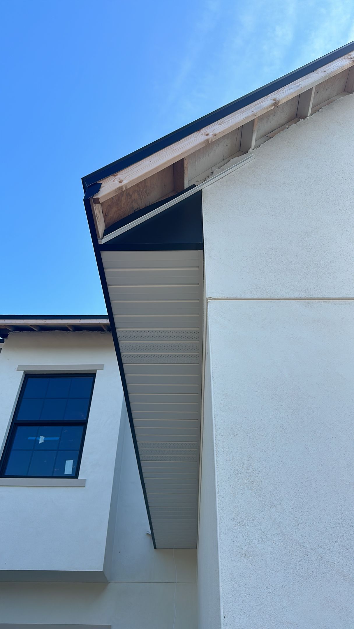 A white house with a black roof and a blue sky in the background.