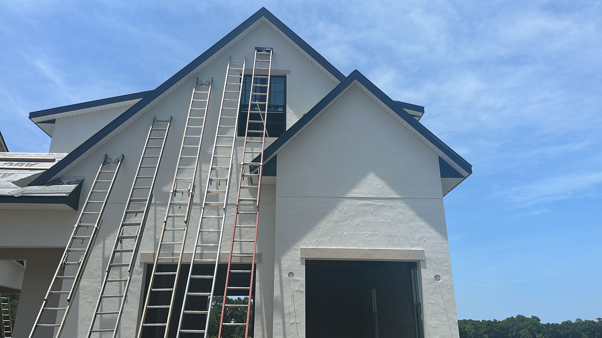 A row of ladders are sitting on the side of a white house.