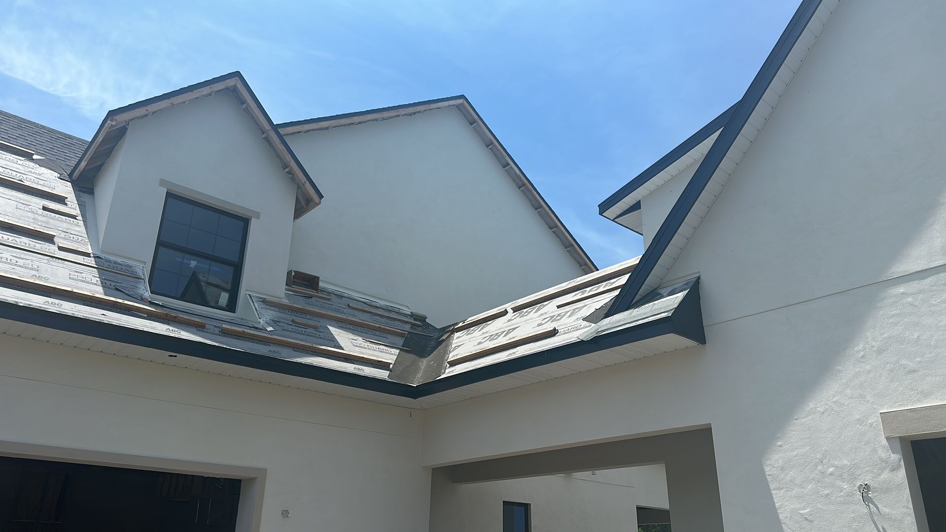 A white house with a black roof and a blue sky in the background.