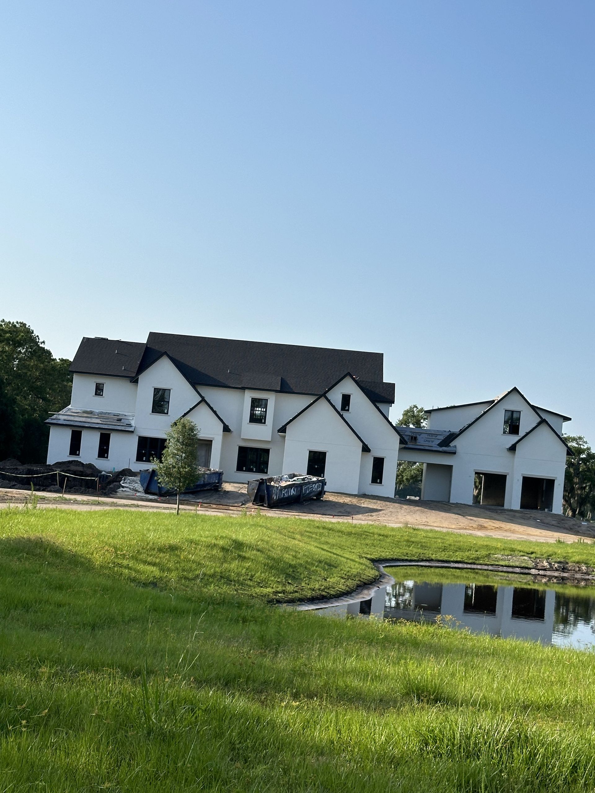 A large white house is being built in the middle of a grassy field.