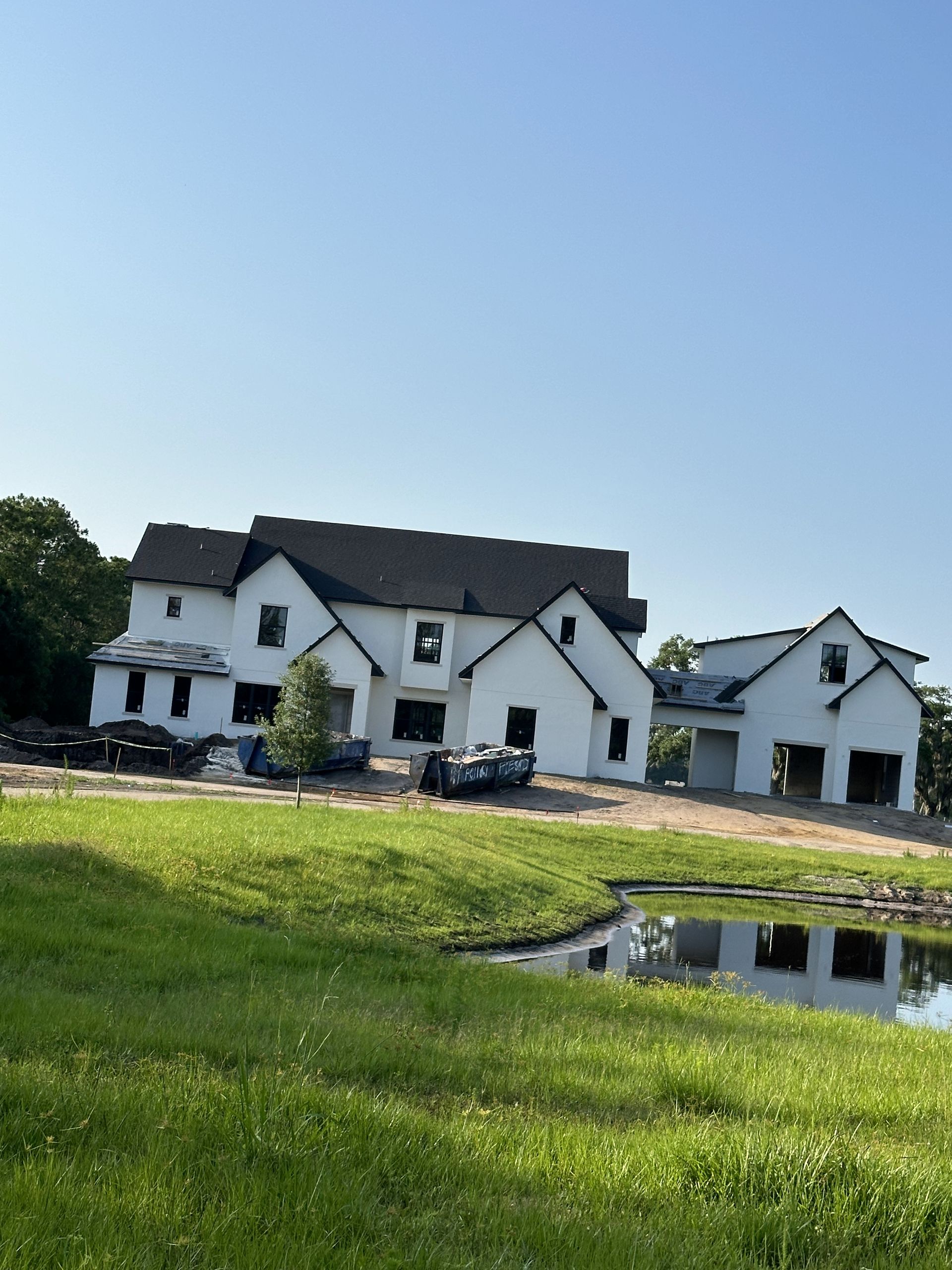 A large white house is being built in the middle of a lush green field.
