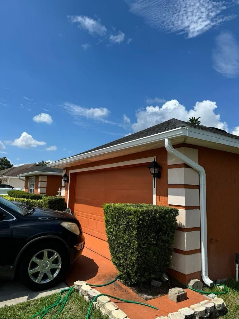 A car is parked in front of a garage with a hose attached to it.