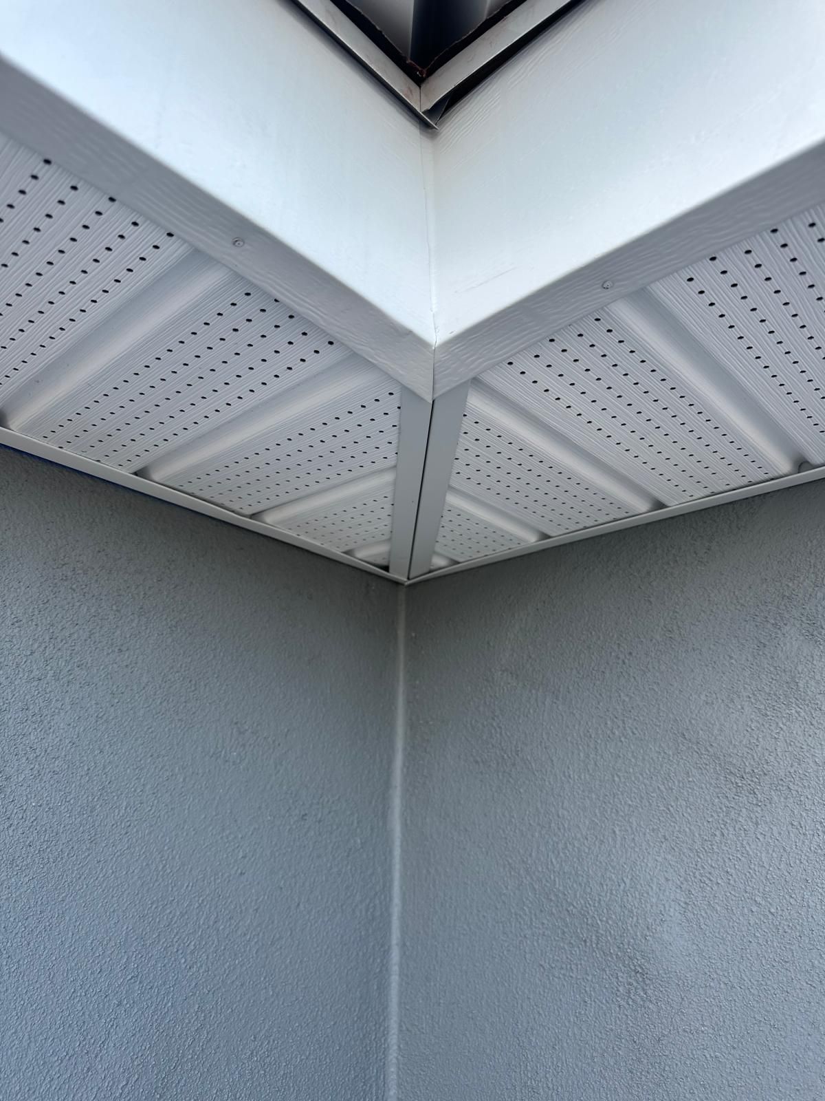 A corner of a building with a white ceiling and a gray wall.