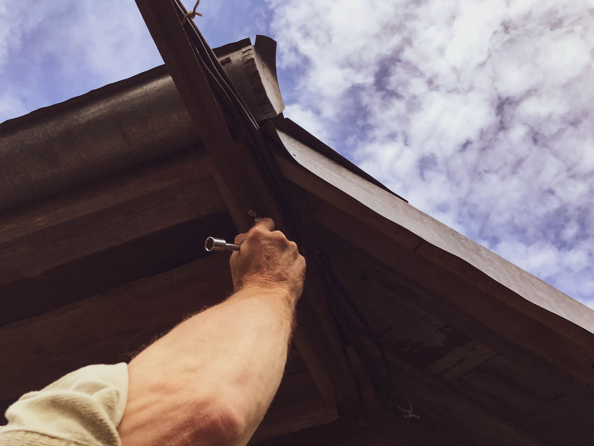 A person is working on a roof with a wrench