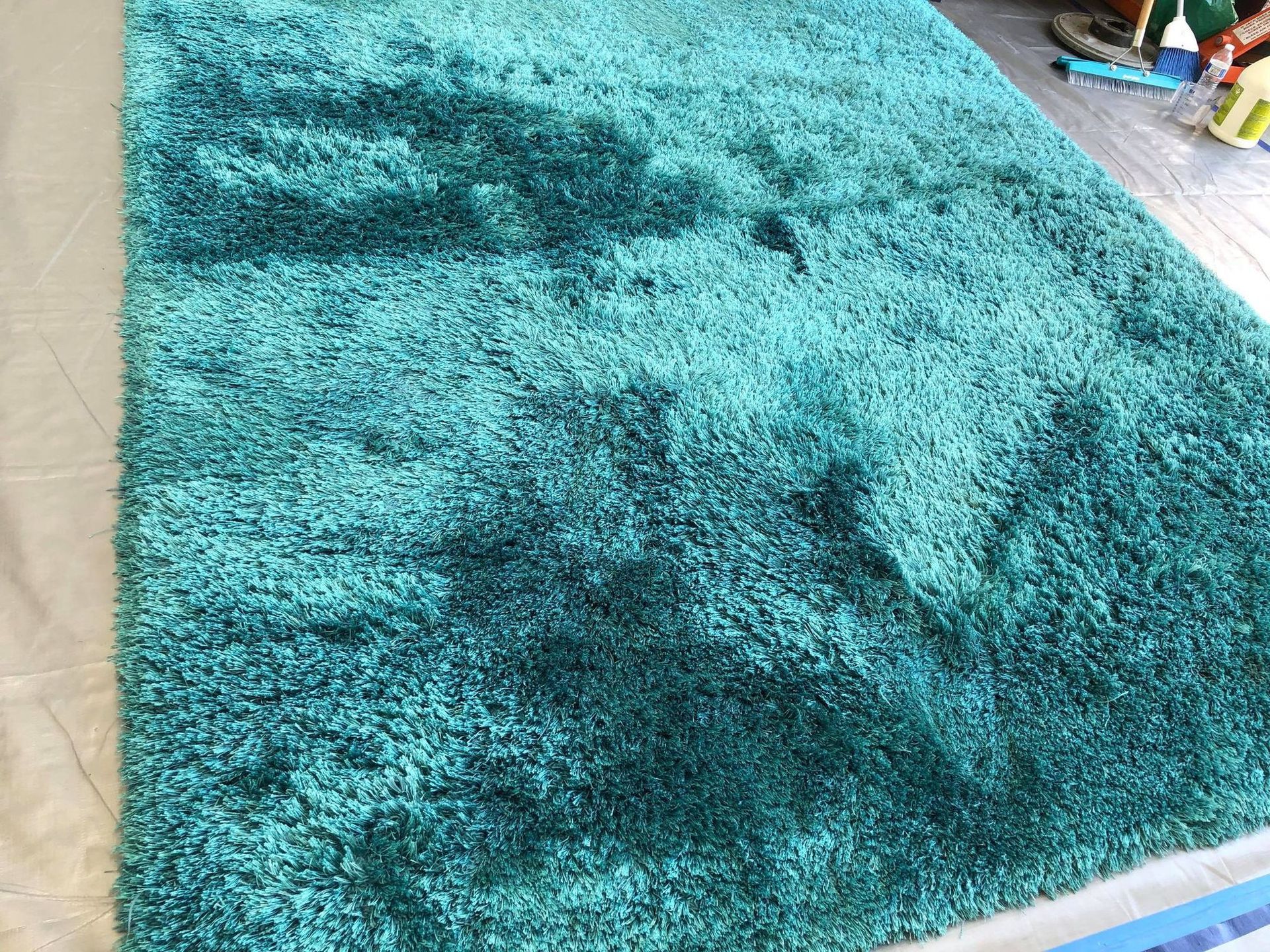 A large green rug is sitting on top of a wooden floor.