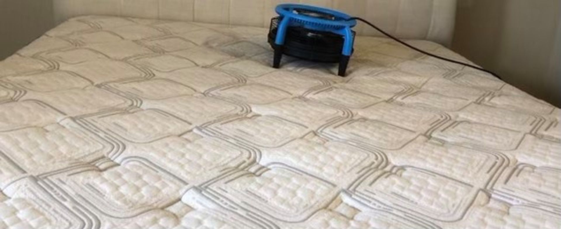 A mattress with a fan on top of it in a bedroom.