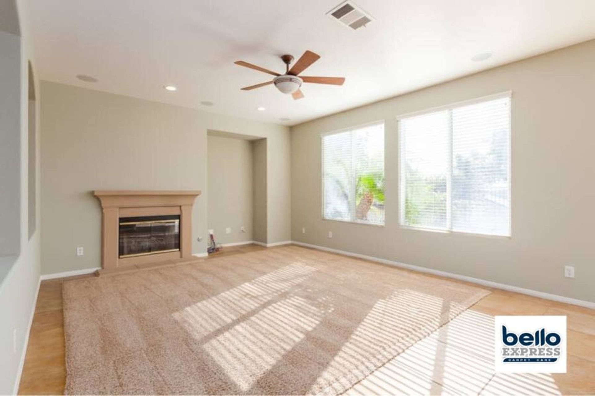 An empty living room with a fireplace and ceiling fan