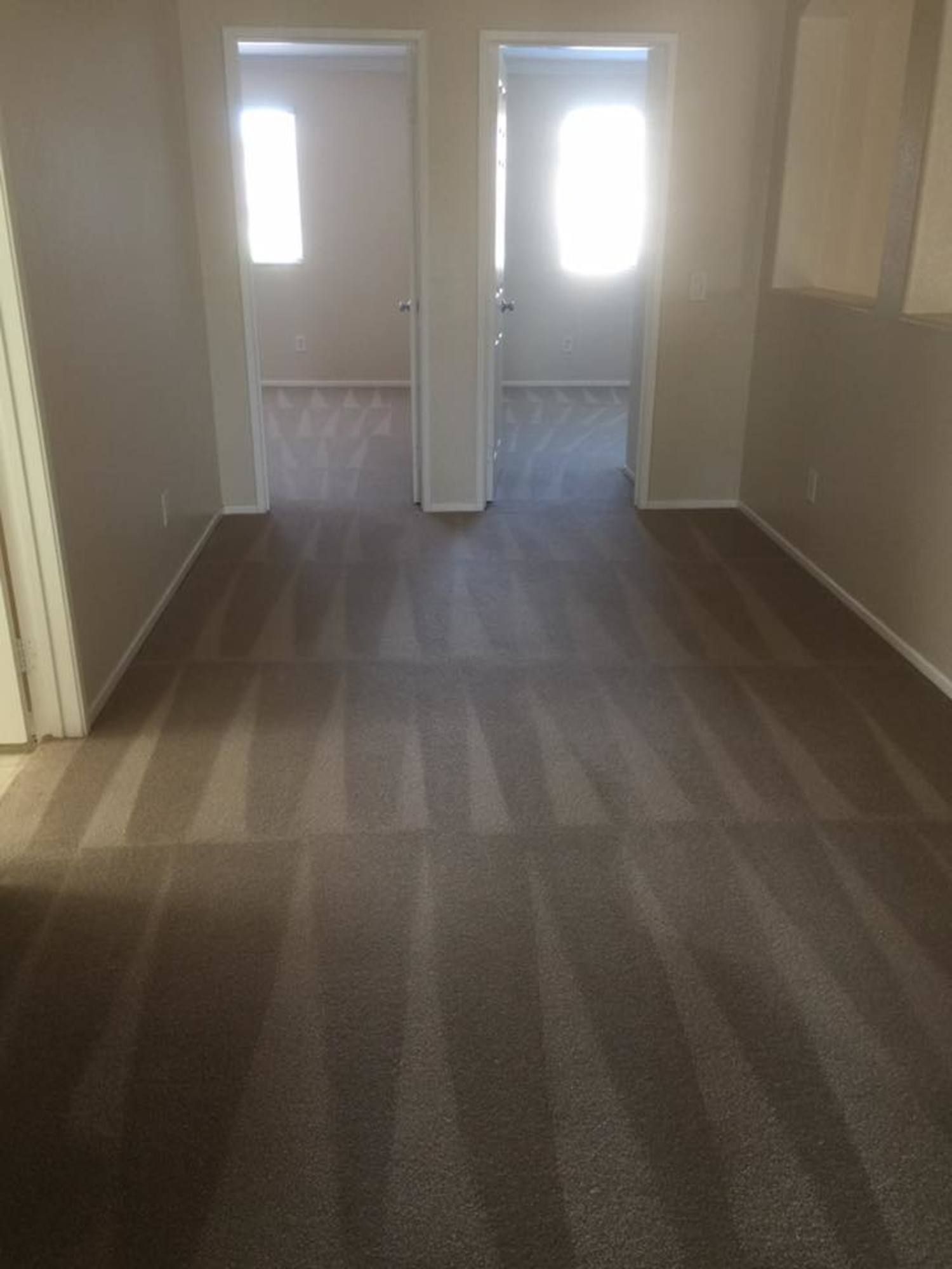 An empty room with two doors and a carpeted floor.