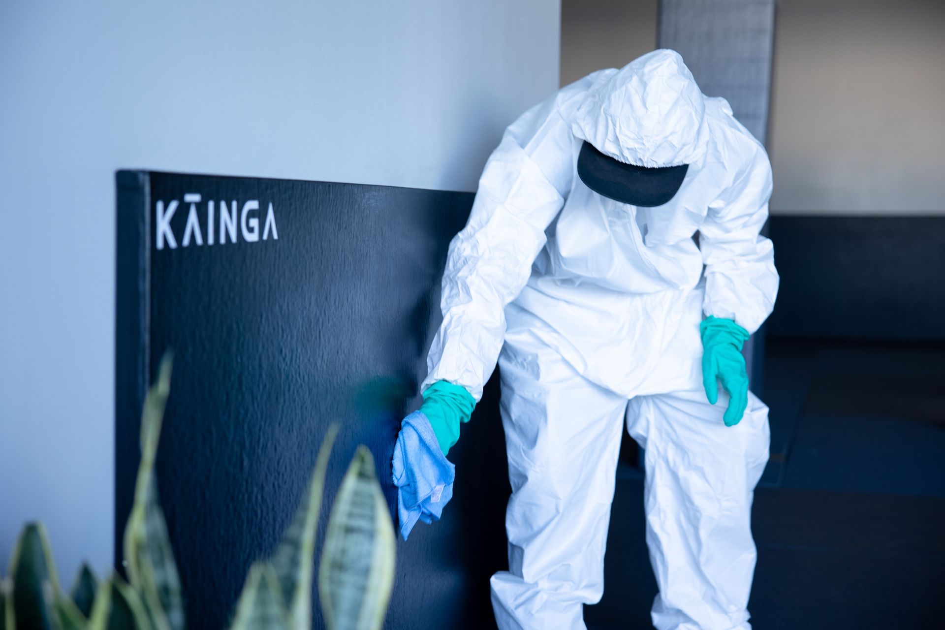 A man in a protective suit is cleaning a wall.