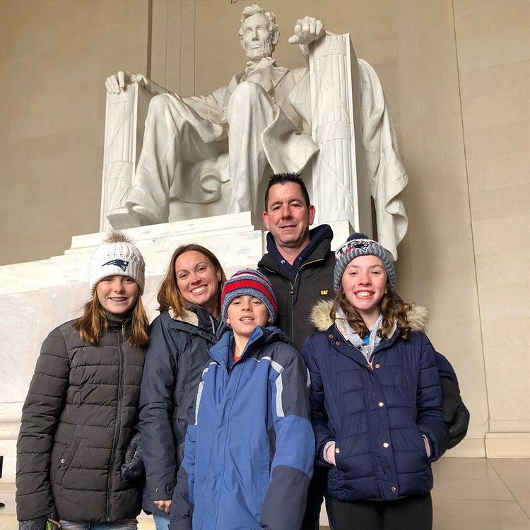 Group posing indoors in winter coats before the Lincoln Memorial statue