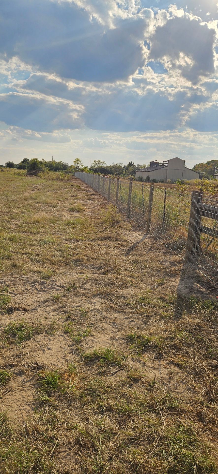 A field with a fence under a cloudy sky.