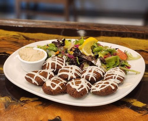 A plate of food with falafel and a salad on a table.