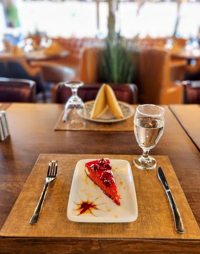 A slice of cheesecake is on a plate on a table.