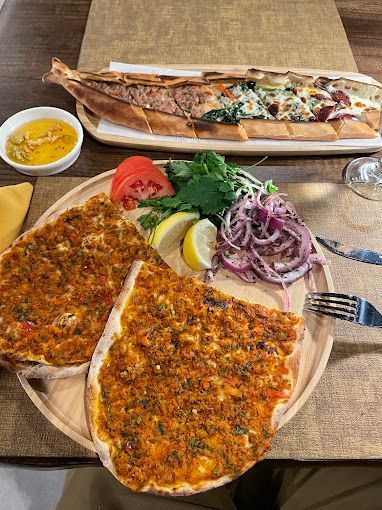 Two pizzas are sitting on a wooden plate on a table.