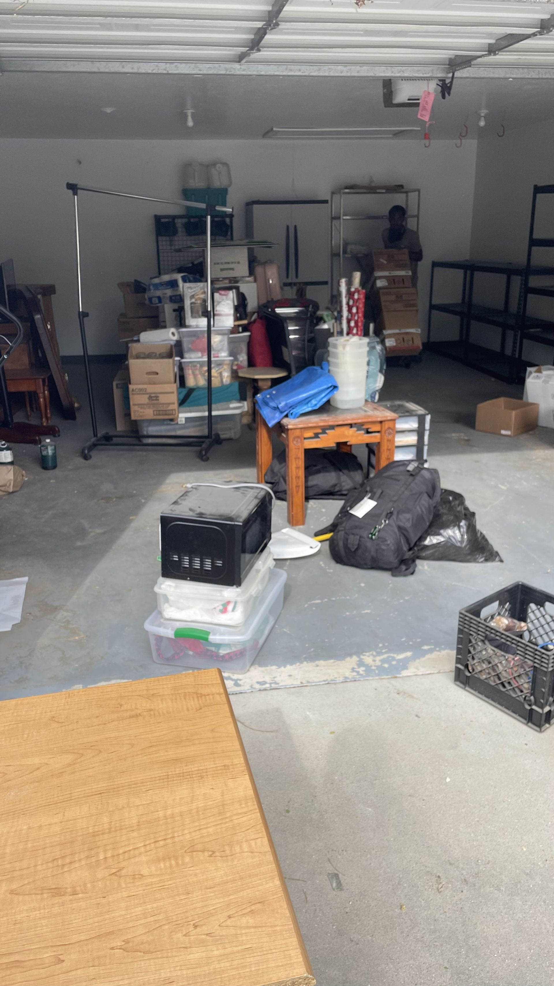 Cluttered garage with boxes, furniture, and equipment, in a cement floored space.
