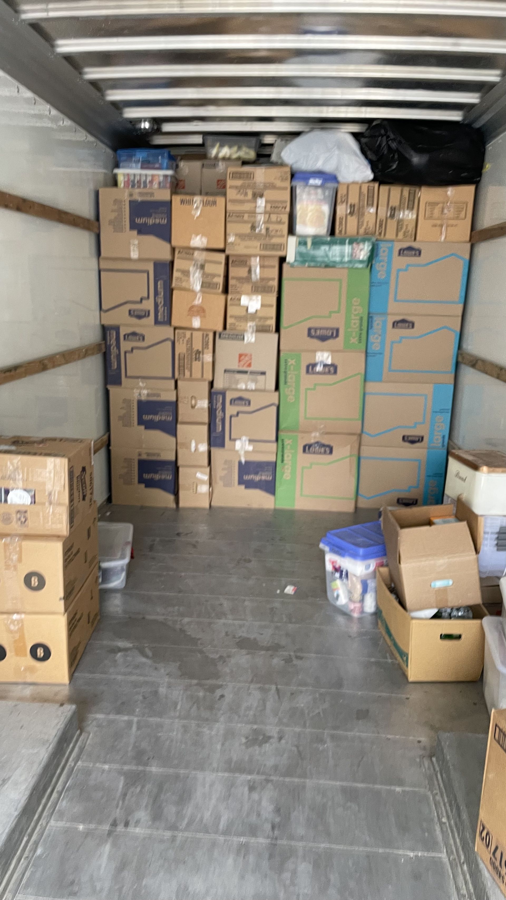 Moving truck interior packed with cardboard boxes and containers.