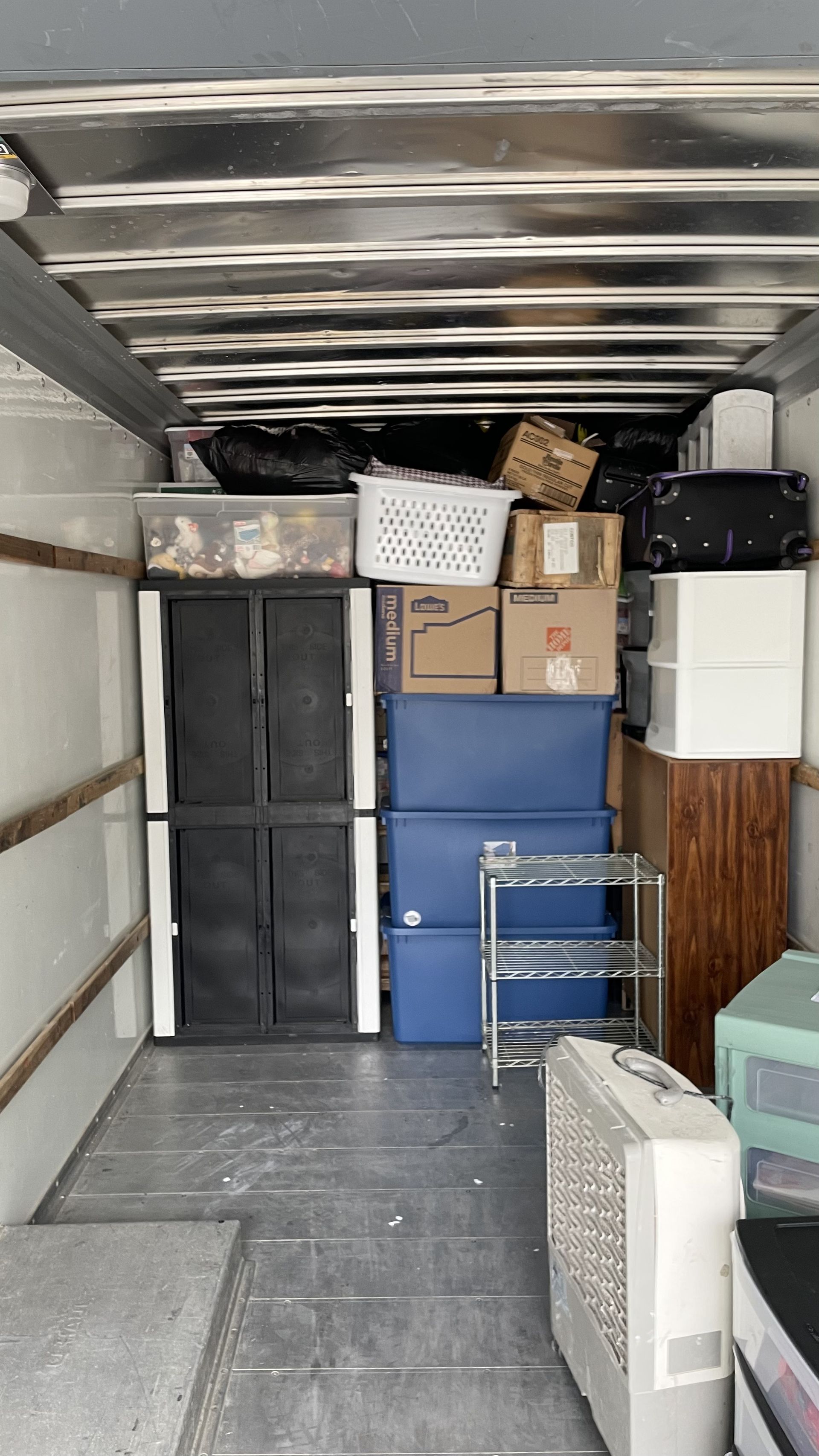 Inside of a truck, packed with boxes, bins, and furniture for moving.