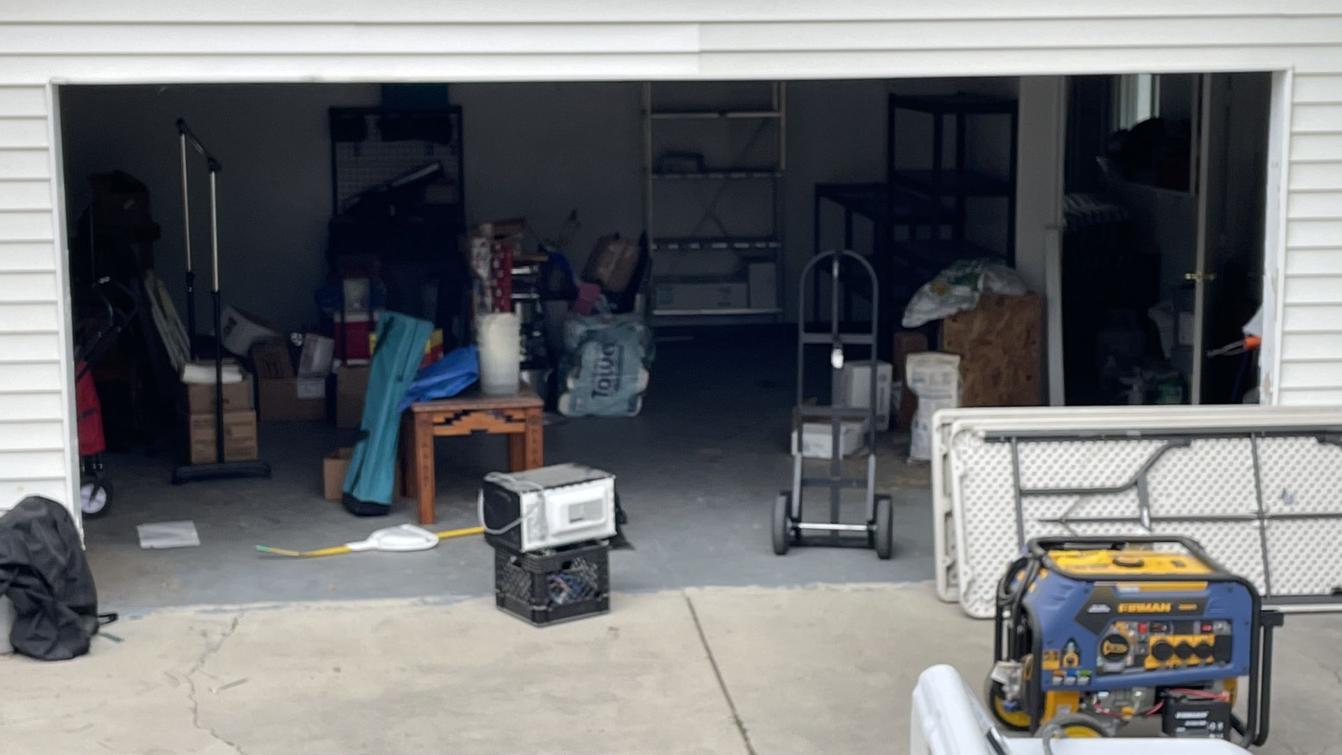 Garage interior with open door; two generators, clutter, and a hand truck.