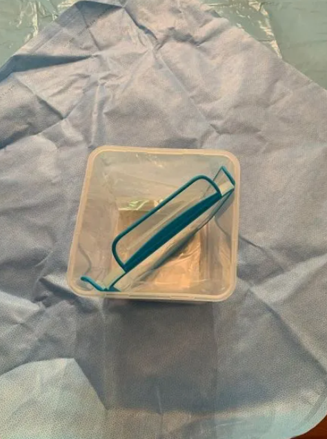 A plastic container with a blue handle sits on a table