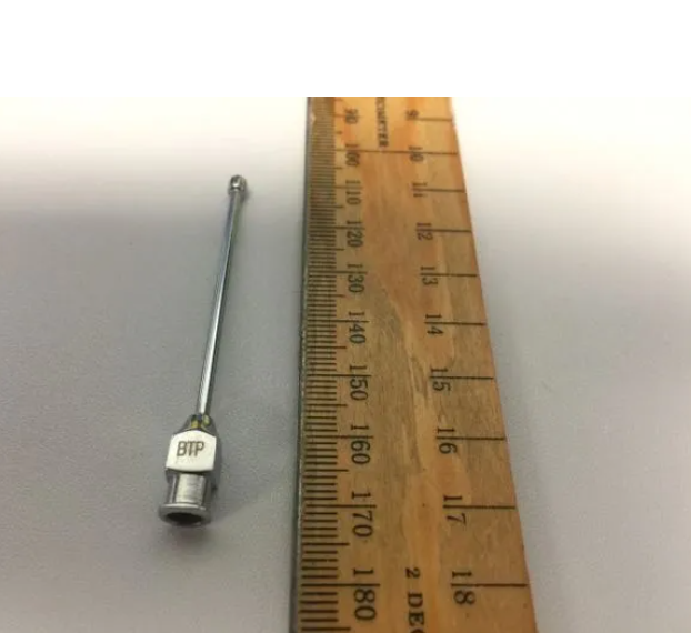 A wooden ruler with a needle next to it