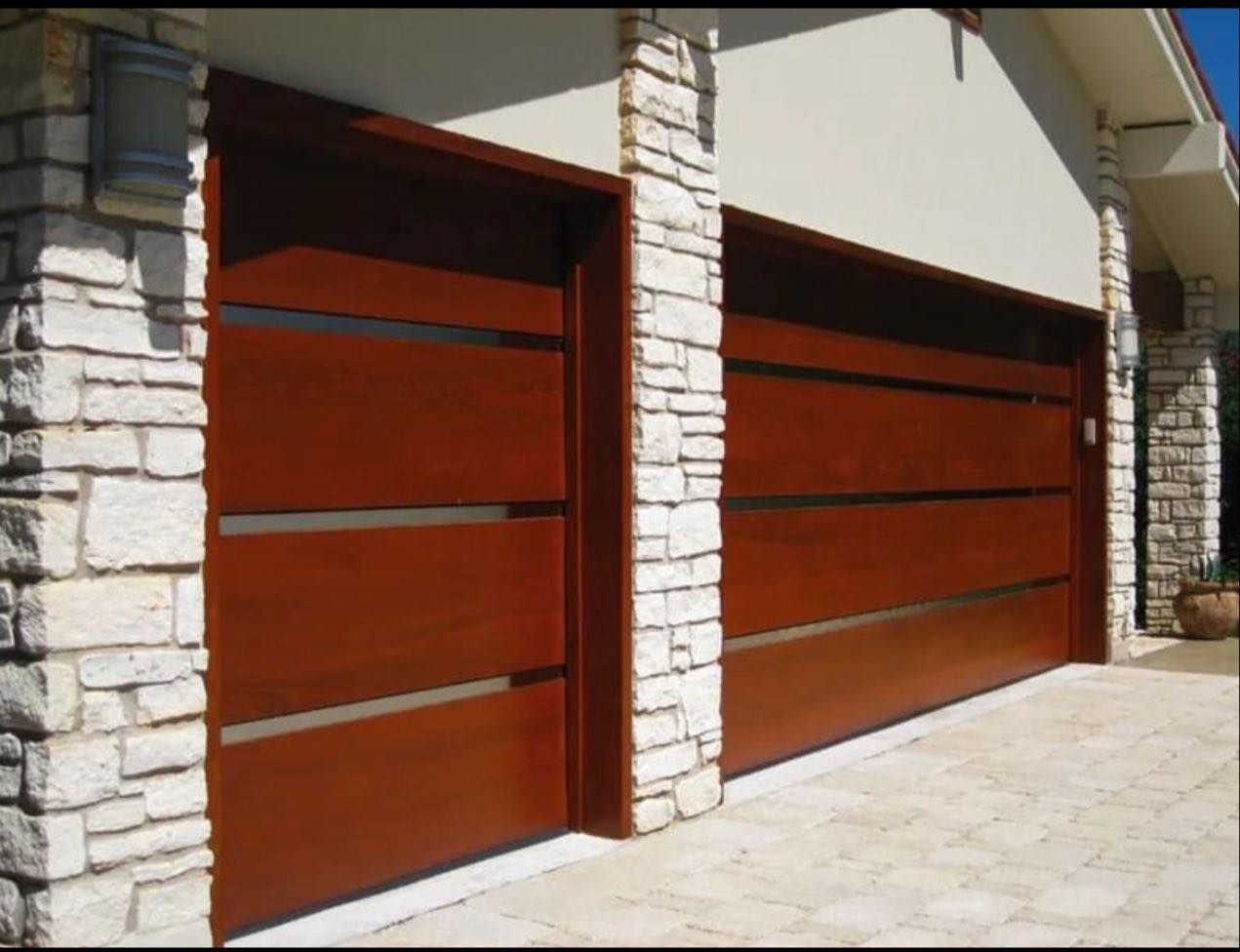 Two brown wooden garage doors with horizontal glass insets, framed by stone columns.
